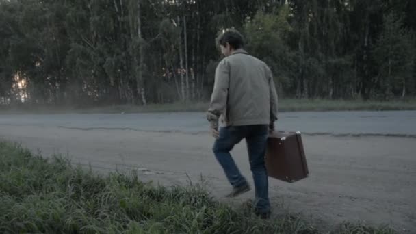 Un homme avec une vieille valise marche sur la route de campagne — Video