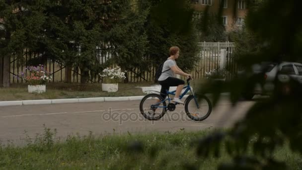 Una mujer adulta en gafas monta en bicicleta — Vídeos de Stock