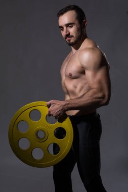 Halter alıştırmalar yapan kaslı vücut geliştirmeci adam