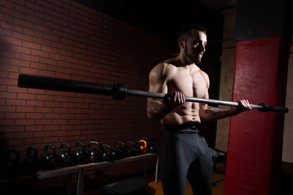 Junger muskulöser Mann mit Langhantelstange im Fitnessstudio — Stockfoto