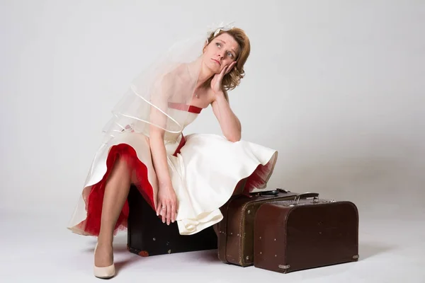 Sorgliga bruden med resväskor på vit bakgrund i studio — Stockfoto