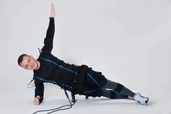 Uyarılması için elektrikli bir kas elbiseli adam egzersizleri yapar — Stok fotoğraf