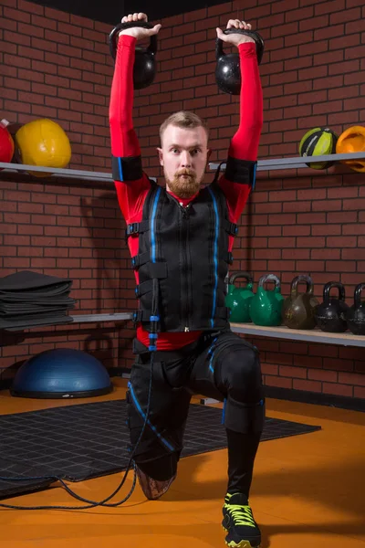 Red-haired man in an electric muscular suit for stimulation with weights — Stock Photo, Image