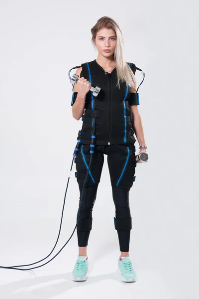 Belle blonde en costume musculaire électrique pour la stimulation avec des haltères — Photo