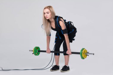 Güzel sarışın uyarıcı için elektrikli bir kas takım elbise içinde bir halter ile egzersizleri