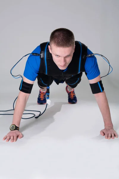 Man in een elektrische gespierde pak voor stimulatie doet push-up. — Stockfoto