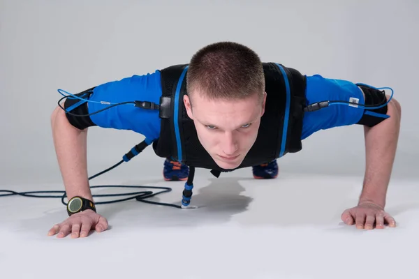 Man in an electric muscular suit for stimulation does push-up. — Stock Photo, Image