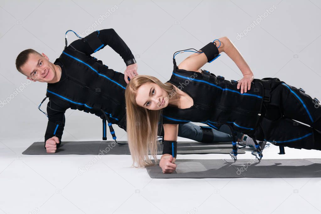 Young man and a woman in an electric muscular suit are trained to stimulate themselves