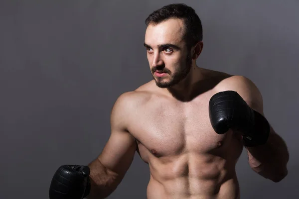 Retrato de um jovem homem musculoso em luvas de boxe em uma pose — Fotografia de Stock