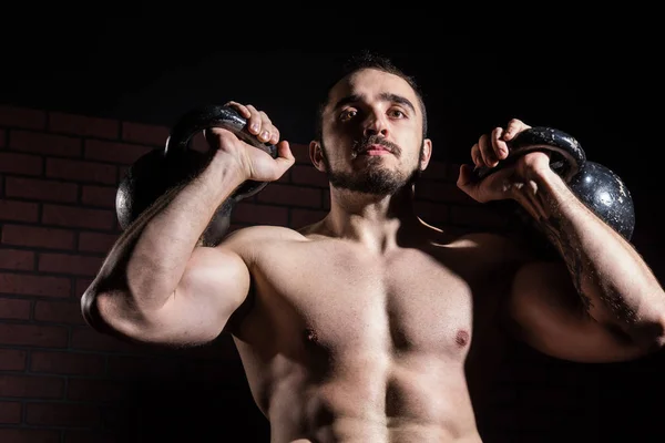 Kaslı adam close-up iki kettlebell asansörleri — Stok fotoğraf