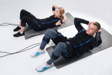 Genç adam ve bir kadın bir elektrik kas elbiseli kendilerini uyarmak için eğitim