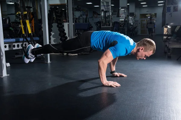 Hombre en el gimnasio hace flexiones con las piernas en la suspensión — Foto de Stock