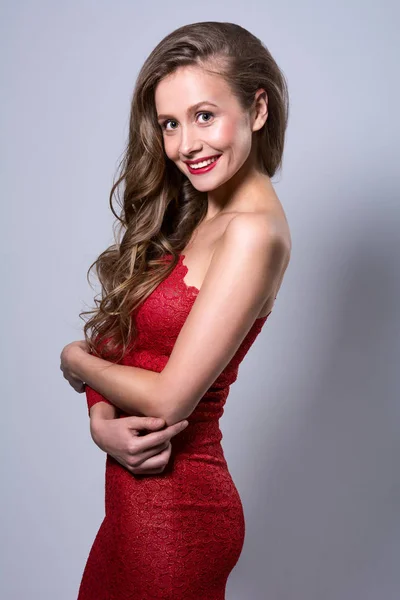 Egy mosolygó fiatal nő, egy piros ruhás portréja — Stock Fotó