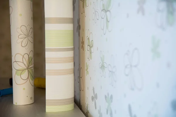 Dos rollos de soporte de papel pintado contra la pared con papel pintado floral —  Fotos de Stock