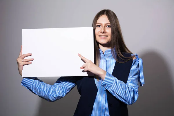 Jonge lachende vrouw wijst op een leeg wit vel — Stockfoto