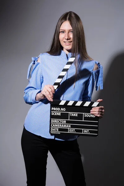 Smiling young woman with movie clapper