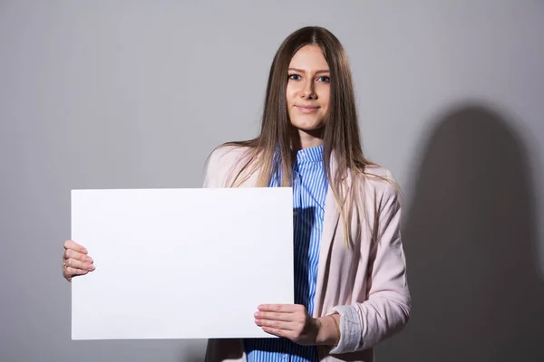 Mooie jongedame in een jasje met een leeg vel — Stockfoto