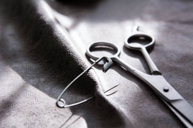 Makas ve pütürlü yüzeyi ile gri kumaş üzerinde bir PIN