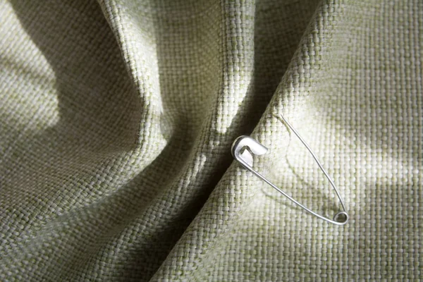 Tecido sintético verde dobrado com pino de metal — Fotografia de Stock