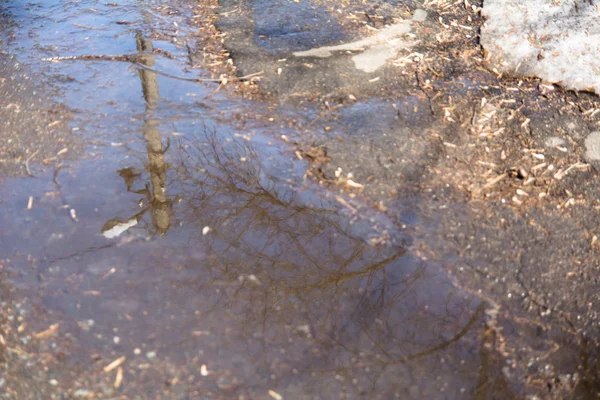 Ondulações e reflexões em uma poça de primavera e neve derretida na cidade — Fotografia de Stock