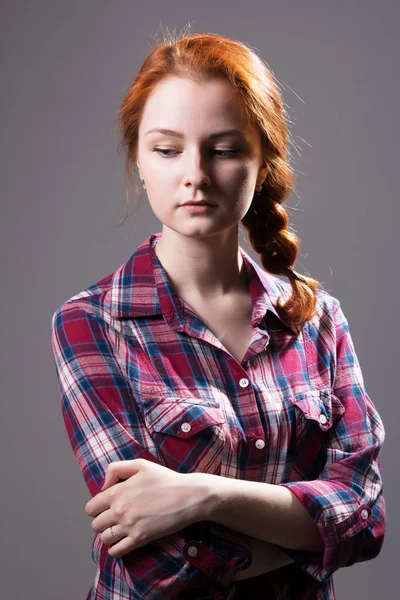 Young red-haired girl with a pigtail in a plaid shirt — Stock Photo, Image