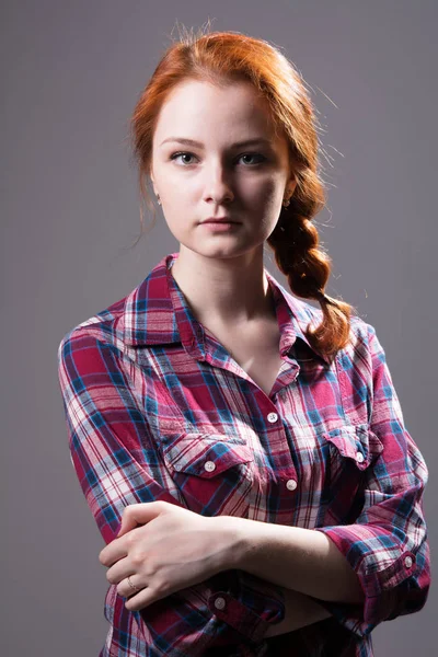 Young red-haired girl with a pigtail in a plaid shirt — Stock Photo, Image