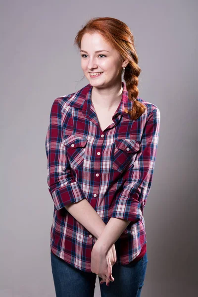 Portret van een lachende jonge vrouw in een plaid shirt — Stockfoto