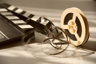 Arka planda sarılı olmayan dar bir retro film şeridi ve film klasörü. Sinema film aksesuarları
