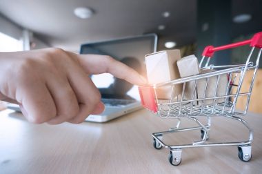 Kadın işaret parmağı ile Internet bağlantılı küçük alışveriş sepeti iterek