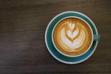 Tahta masada bir fincan sıcak latte sanat kahvesi.