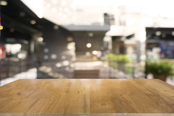Prázdné tmavý dřevěný stůl před abstraktní rozostřeného pozadí — Stock fotografie