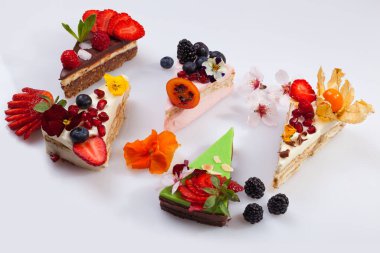 Renkli meyveli beş dilim pasta ve beyaz bir arka planda düzenlenmiş..