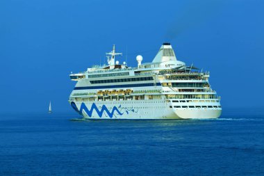 Açık denizlerde seyreden bir gemi ve önünde de bir yelkenli.