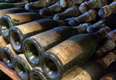 Şarap mahzenindeki raflarda dizilmiş eski şarap şişeleri..