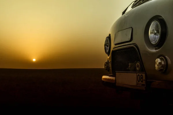 Старовинний ретро автомобіль на червоному заході сонця в пустелі Стокове Фото