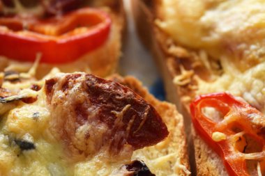 Slice of fried sausage on toast with cheese and peppers