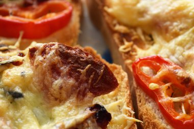 Slice of fried sausage on toast with crunchy cheese and peppers