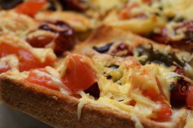 A piece of  tomato with a wrinkled skin on toast with melted cheese