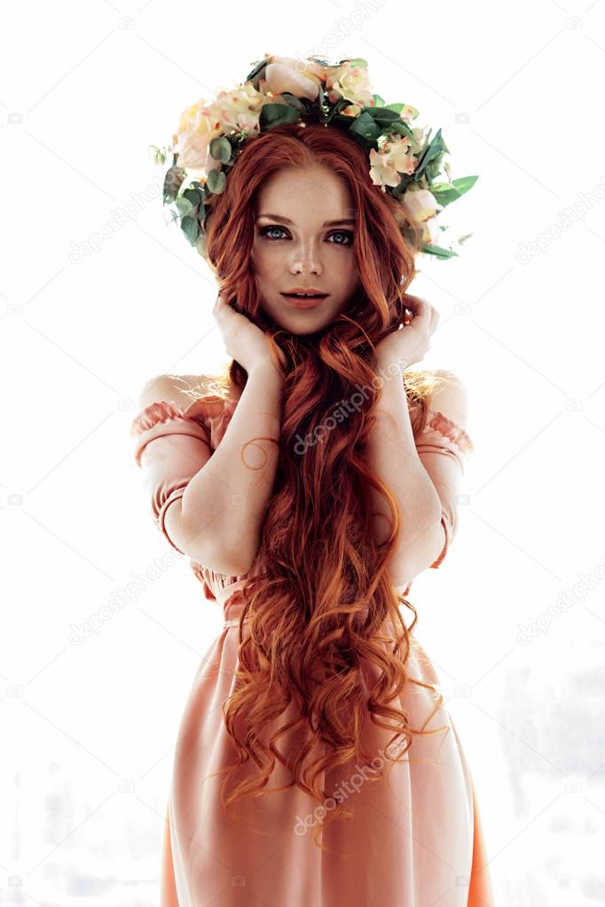 beautiful unusual girl with long red hair in a wreath on the head
