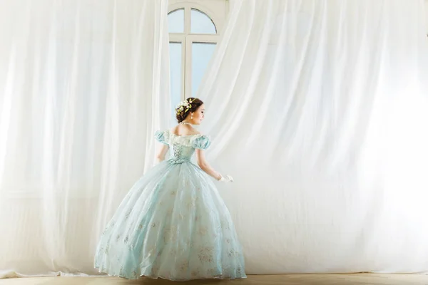 歴史的なドレスを着て 高い窓のエレガントな女性を真っすぐカーテン ダンス パーティーに友人を待っていると — ストック写真