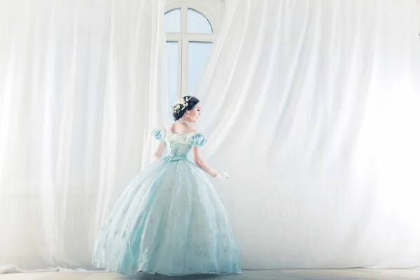 优雅的女人在一个高窗口的历史性礼服 拉直窗帘 并等待朋友舞会跳舞 — 图库照片