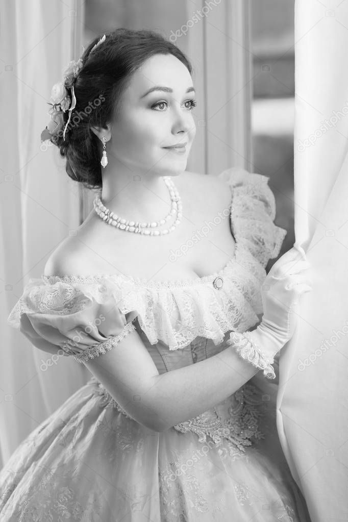 Black and white Elegant woman in historical dress and in jewelry waiting for friends at the ball to dance