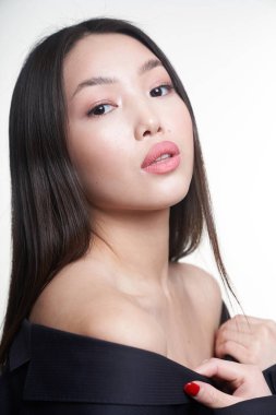  Portrait of a young beautiful Asian girl looking directly at the camera, shoulders open, hands pressed to her chest. The concept of skin care facial, makeup                                  