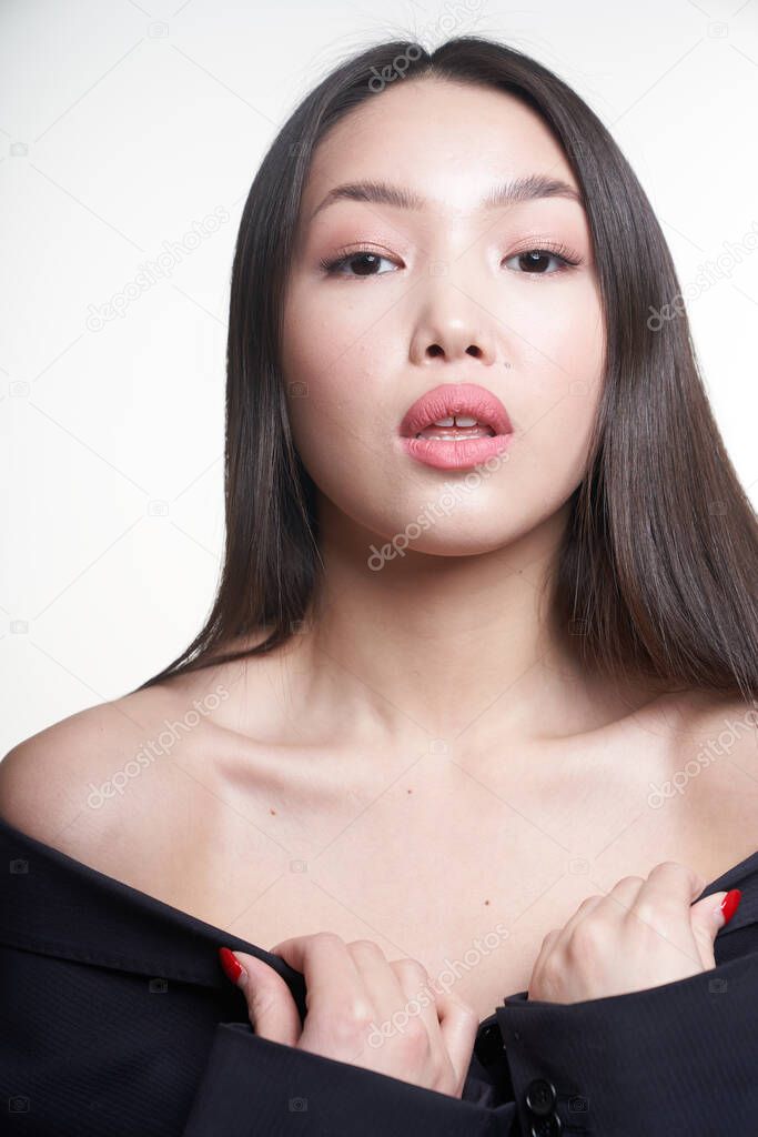  Portrait of a young beautiful Asian girl looking directly at the camera, shoulders open, hands pressed to her chest. The concept of skin care facial, makeup                                                    
