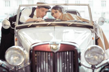 Yürüyüş sırasında genç bir çift eski bir arabanın yanında duruyor. Kadın, arabanın içinden adama uzanıyor. Tarihi yeniden yapılandırma