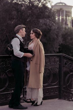 Genç bir çift çitin yanında dikilirken birbirlerinin gözlerinin içine bakar. Eski moda giysiler. Tarihi yeniden yapılandırma