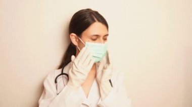 Steteskoplu bir doktor eldivenli tek kullanımlık mavi bir maske takar ve hazır bir ilaçla bir şırınga alır.