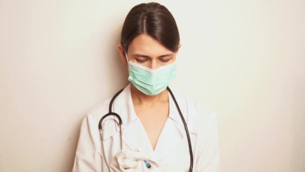 青いマスクと使い捨て手袋の女性医師が使い捨て注射器を取り出し手を治療する — ストック動画