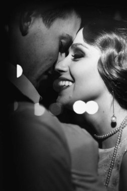 Genç bir kız ve bir adamın siyah beyaz yakın plan fotoğrafı. Erkeğine sarılıyor ve gülüyor. Hem de retro kıyafetlerle. Tarihi yeniden yapılandırma.