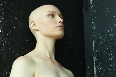 Siyah bir arka planda, saçları açık omuzlu, ciddi bir genç kız.